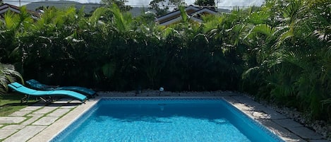 Private pool nestled by a perimeter fence of palm trees, ample furnishing, bbq