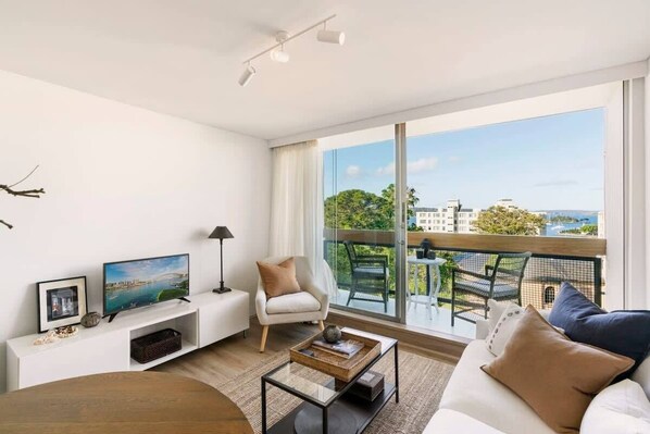 Our lovely, comfy living space with balcony + view of our charming neighborhood and the ocean!