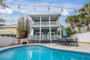Large polywood table and 6 chairs with umbrella view seated across the pool