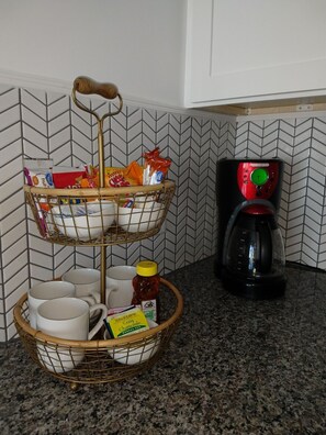 Coffee maker with starter snacks and coffee/tea condiments.