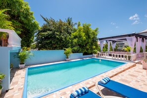 A vibrant poolside sanctuary, where crystal-clear waters meet an array of colors and textures, beckoning for a moment of relaxation beneath the sun-kissed canopy