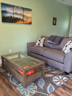 Living room with sleeper sofa and roll away coffee table.