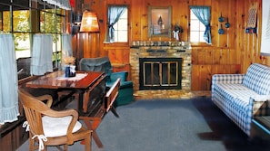 Comfortable gathering area with wood-burning fireplace, TV, A/C & dining table.