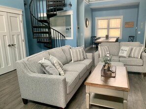 den area with dining room table in the back and spiral staircase leading to loft