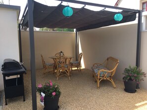 Espace sous pergola dédié aux vacanciers avec barbecue.
