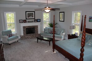 Owner's suite with King-sized bed, fireplace, 55" HDTV, and door to back porch.