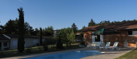 Vue coté piscine sur le poolhouse en bois et la maison 