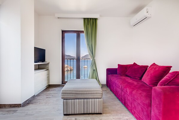 Living room with flat screen TV, air - conditioning and sofa bed. 