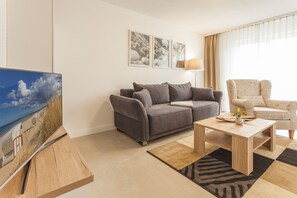 Wohnbereich mit gemütlichem Ohrensessel und bequemem Sofa mit Schlaffunktion.