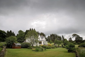 View of farmhouse from large, mature gardens.