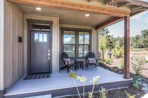 Digital keypad entry and Adirondack chairs on covered front porch. 