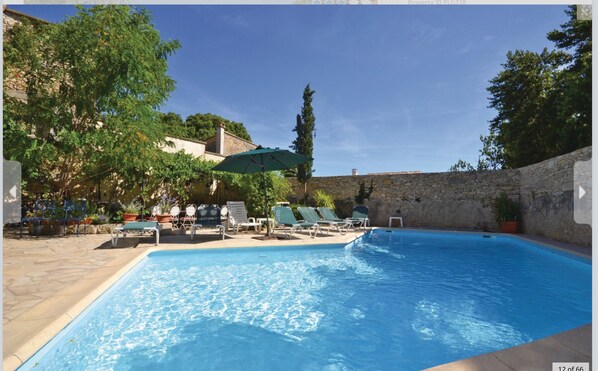 Large swimming pool, sunloungers and covered table and chairs.
