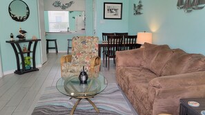 This view shows the living room and dining area with kitchen in the background