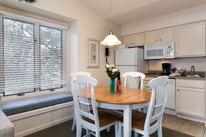 The unit includes a charming window seat, a dining table for four, and a fully-equipped kitchen for a cozy and functional living space.