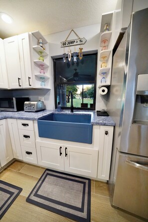 Open plan kitchen includes farmhouse sink, garbage disposal, cookware, bakeware