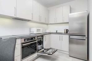 A sleek kitchen featuring white cabinetry, stainless steel appliances, and an organized countertop, offering a clean and functional cooking area.
