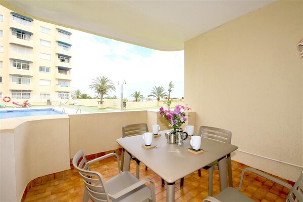 Private terrace with outdoor dining area for four guests and pool views
