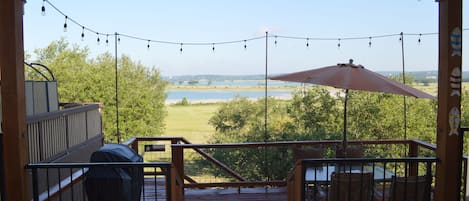 Lake view from porch. Deck just below with table, chairs, gas grill, and lights.