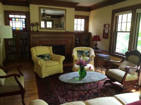 Living room with large picture window overlooking windowbox, fireplace.