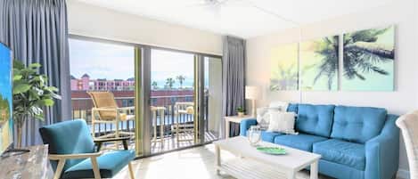 Relax in this coastal casual beach condo - living room walks out onto patio and has a 65" TV