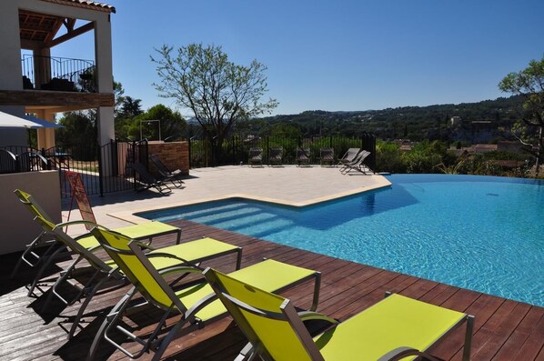 Piscine chauffée à débordement, vue sur un village médiéval.