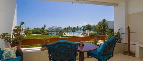 Terraza con una pequeña mesa y sillas, vistas expansivas al mar