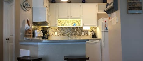 Newly updated kitchen with glass backsplash and under cabinet lighting.