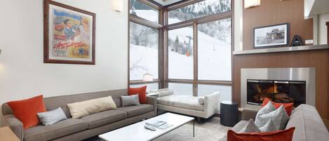 The warm and inviting living room features a gas fireplace, flat screen TV, plenty of seating and views of Aspen Mountain.