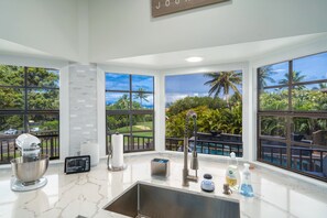 Cook in style with expansive windows showcasing lush garden and pool views, creating a relaxing atmosphere perfect for any meal preparation.