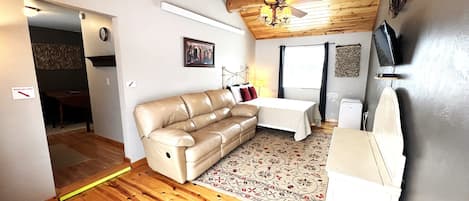 Living room with recliner couch, Full size bed and AC unit