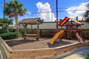 Play area by pool with grills and picnic tables