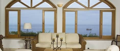 Living room with arched windows and sliding glass doors on both sides to decks. 