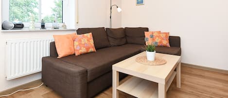 Wohnzimmer mit integrierter Küche und räumlich abgeteiltem Esszimmer-Abteil