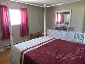 A large bedroom with a Queen size bed, dresser & armoire.