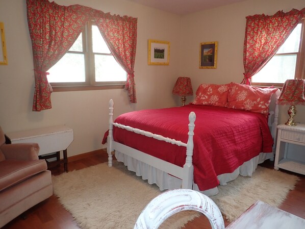 Armchair, double bed with night tables & lamps, two windows, desk, 2 white rugs