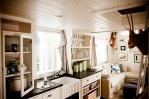 Kitchenette with view into living area. Small refrigerator and stovetop. 