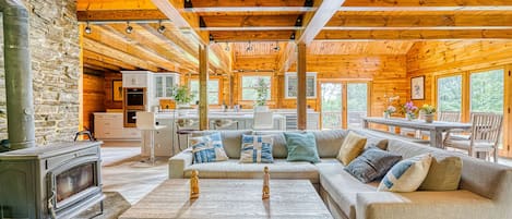 View of the wood-burning stove, sectional sofa, kitchen and dining area