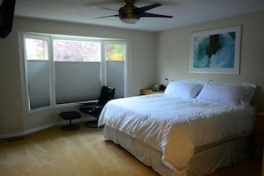 Comfortable master bedroom includes king-sized bed, recliner, television, and full en-suite bathroom.