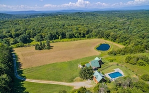 View of the hayfield, pond, main house, pool house and pool