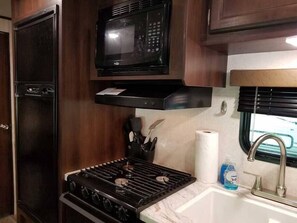 Kitchen is stocked with cooking utensils and serviceware.