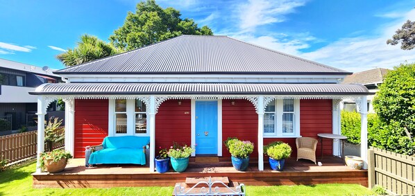 sunny north facing veranda with comfty couch, flowers and lush grass