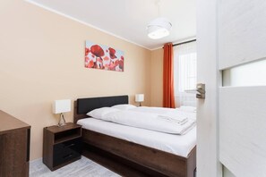 A cozy bedroom with a double bed, bedside table, and a colorful painting on the wall.