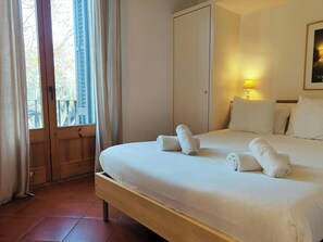 The bedroom features a comfortable queen-sized bed with crisp white linens and fluffy towels, ready for a relaxing stay.  The room is bathed in natural light from the large windows, offering a glimpse of the vibrant city outside.
