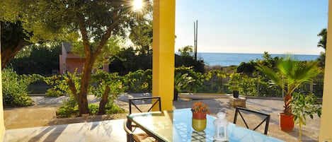 Large covered terrace with garden furniture and a view of the sea.