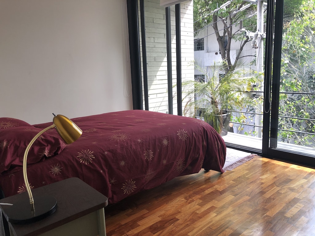VRBO Mexico City: Minimal style bedroom, with large bed and sliding glass door opening onto a balcony