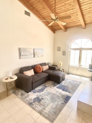 Living room with pull out sofa, storage chaise,  flat screen & vaulted ceiling.