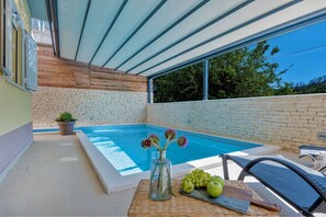 Covered spacious swimming pool with deckchairs to enjoy on the outdoor terrace of the property of the Croatian luxury villa LeLu