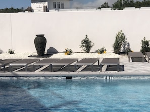 Relaxing pool courtyard with lounge chairs, water features, and landscaping.