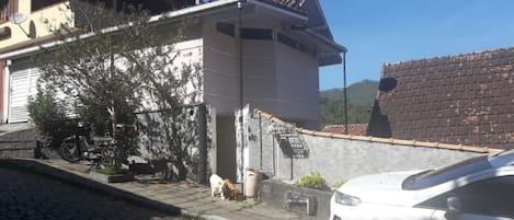 A Fachada da casa toda em cor salmão e com local para estacionamento. 