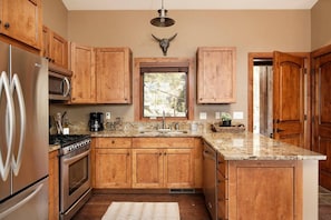 Well-appointed kitchen with gas range and full utensils and cookware.